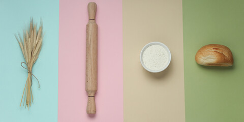 Spikelets of wheat, rolling pin, flour, bun on a pastel background. Cooking ingredients. Top view