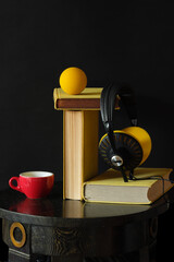 audiobooks concept with heap of yellow books and vintage headphones.Black background with large copy space. Low key shot