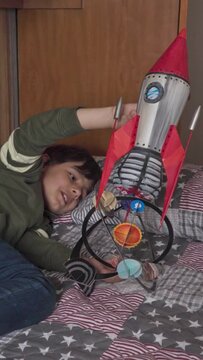 Happy boy playing with a rocket made from refreshment recycled plastic bottle on his bedroom vertical video