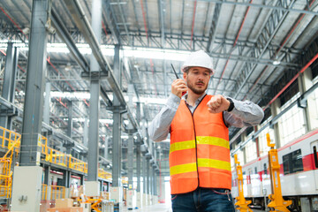 Portrait of a young male technician using a walkie talkie working and standing in a skytrain repair station.