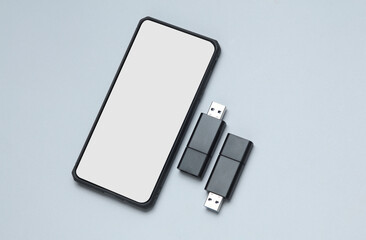 Smartphone and Two black USB flash drives on a gray background