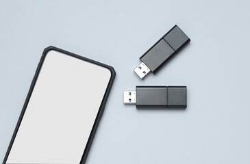 Smartphone and Two black USB flash drives on a gray background