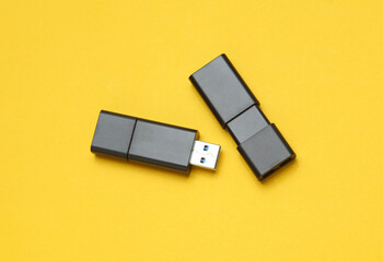 Two black USB flash drives on yellow background