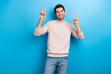 Photo of good mood positive handsome man with stylish haircut dressed beige pullover showing v-sign...