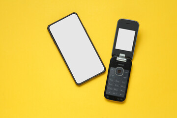 Retro flip mobile phone and modern smartphone on yellow background