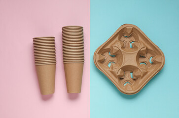 Stack of disposable cardboard cups  and tray on blue pink background