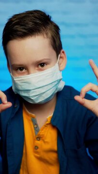 Child showing thumb up wearing protective face mask. Concept for Protecting Coronavirus. Stop coronavirus. Stay at home Vertical video
