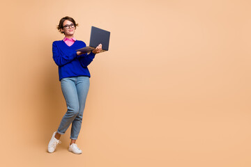 Full body photo of corporate economist lady hold use laptop empty space isolated on beige color background