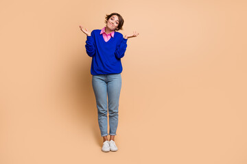 Full body photo of pretty young girl shrug shoulders clueless wear trendy blue outfit isolated on beige color background