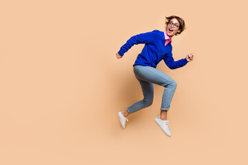Fototapeta na wymiar Full body profile photo of active sporty lady look back empty space jump run isolated on beige color background