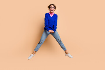 Fototapeta na wymiar Full body portrait of impressed energetic young lady jump empty space ad isolated on beige color background