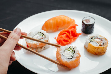 Different types of sushi rolls on white plates on black background top view
