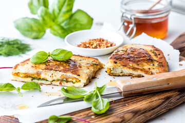 Naan bread breakfast sandwiches on a wooden board with basil and honey.