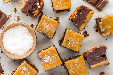 Above view of salted caramel topped brownies, on parchment paper.
