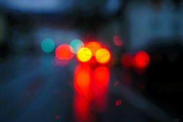 Abstraktes Motiv mit roten und gelben Autolichtern auf nasser Straße mit Spiegelung in Stadt bei...
