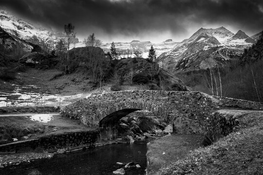 Sunset over the Pyrenees mountains, Circus of Gavarnie and the old stone bridge spanning the stream, High quality photo