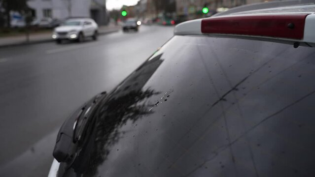 car exterior on the background of a city road. rear window of a car with bird droppings in the foreground. in the background a city road with passing cars out of focus on a cloudy rainy day.