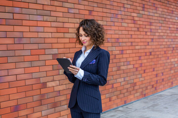 Portrait of a successful business woman in front of modern business building. Young manager poses outside. Female business leader.
