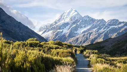 Fototapete Aoraki/Mount Cook Tourist on the trail in beautiful alpine valley facing huge snowy mountain, Mt Cook, New Zealand