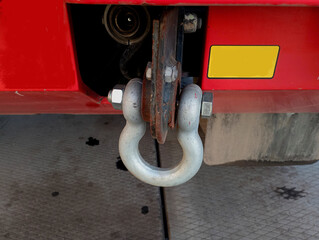 A special metal carabiner for towing transport from behind a red truck. A large metal hook for...