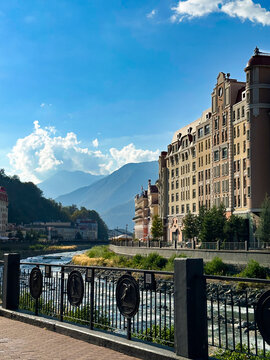 Sunny panorama of Rosa Khutor, Sochi, showing the idyllic mix of Alpine architecture and the rushing river in the Caucasus