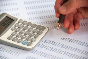 Hand holding pen while doing financial performance analysis. Business strategy and budget concept.