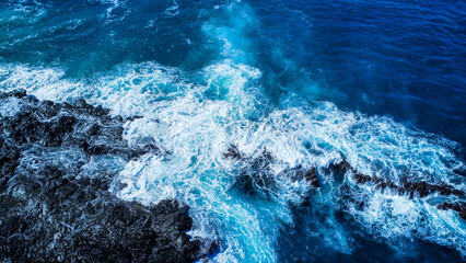 Drone shot of the coast of Hawaii, with blue water on rockface