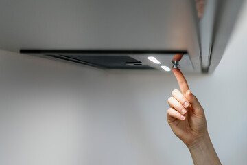 Woman press button on range hood, select quiet mode for air ventilation