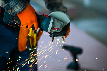 a worker saws a plasterboard profile using an angle grinder