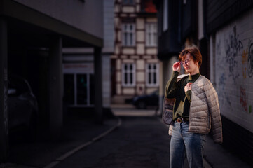 A contemplative woman adjusts her glasses while stylishly draped in a light jacket, set against the...