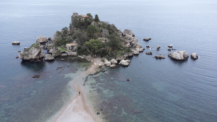 Panoramic view of beautiful Isola Bella, small island near Taormina, Sicily, Italy. Narrow path connects island to mainland Taormina beach surrounded by azure waters of Ionian Sea.