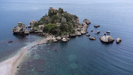 Panoramic view of beautiful Isola Bella, small island near Taormina, Sicily, Italy. Narrow path connects island to mainland Taormina beach surrounded by azure waters of Ionian Sea. - 770872625