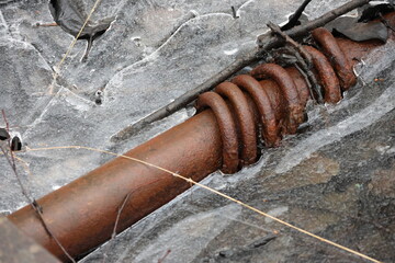 A rusty decorative tube with rings lying outdoors frozen in ice. Stylish background image.