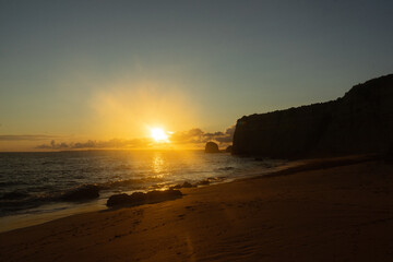 Sunset in Algarve beach with the sun, cliffs and the sand