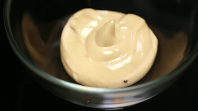 Close-up shot of a rotating small transparent bowl filled with white sauce.