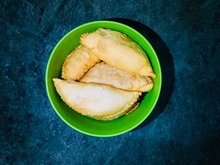 Glorious Gujia: A traditional delight nestled in a vibrant green bowl against a lush green backdrop