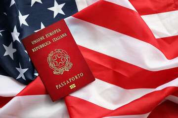 Fototapeta na wymiar Italian passport on United States national flag background close up. Tourism and diplomacy concept