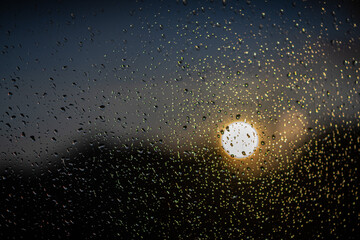 Raindrops on a window, sundown in the background