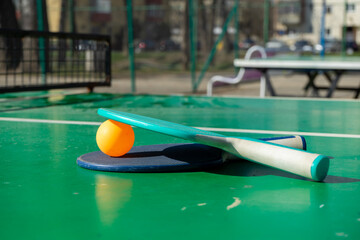 Two rackets and an orange ball on a green table. Ping-pong. Table tennis.