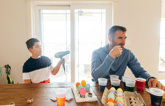 Pointing a hair dryer at an adult male. 