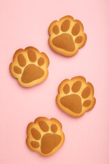 Self made cat paw cookies on pink background. Vertical photo