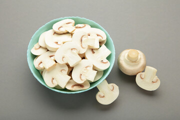 Fototapeta na wymiar Fresh white champignon mushrooms on mint plate on grey background.