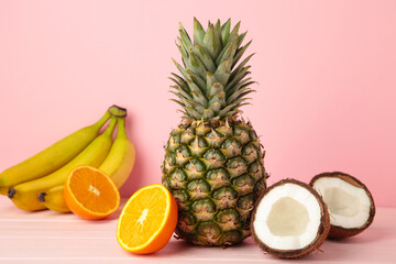 Tropical fruits. Pineapple, coconut, orange and banana on pink background