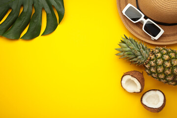 Summer accessories with coconuts on yellow background.