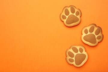 Self made cat paw cookies on orange background.
