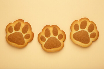 Self made cat paw cookies on beige background.