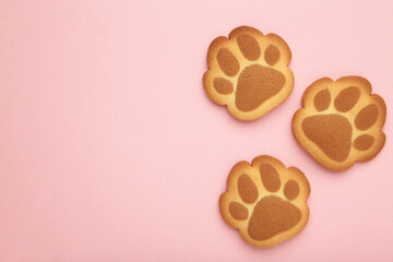 Self made cat paw cookies on pink background.