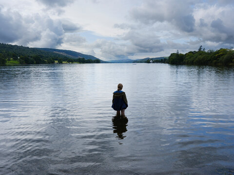 A girl wearing a jacket stands in Coniston Lake
