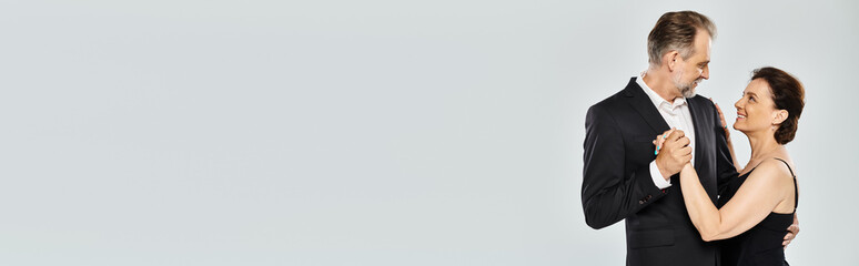 Ballroom dance middle aged couple in a dance pose and smiling isolated on grey background, banner