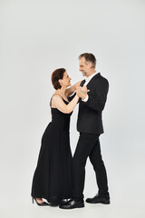 Ballroom dance middle aged couple in a dance pose and smiling isolated on grey background